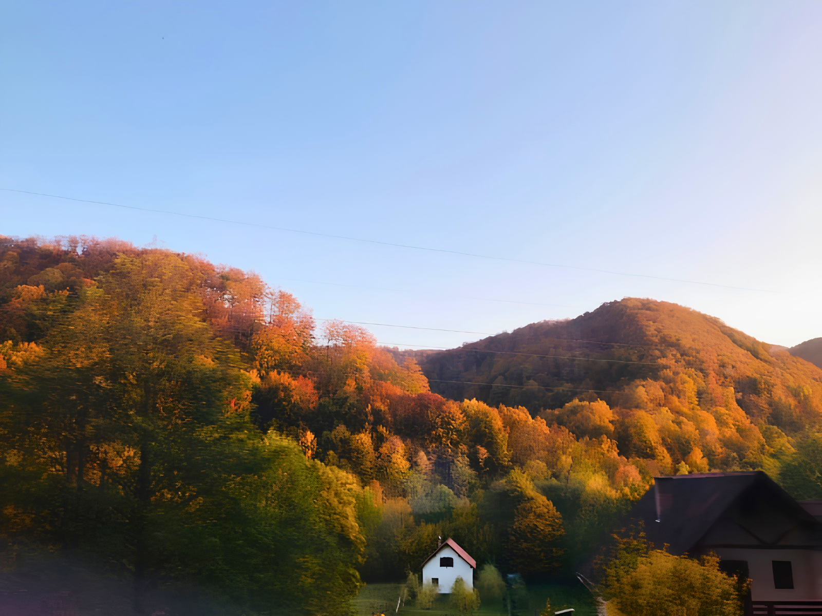 Rolling Romanian hillsides ablaze with autumn colour — orange, red and gold — a lone white farmhouse tucked into the valley below.