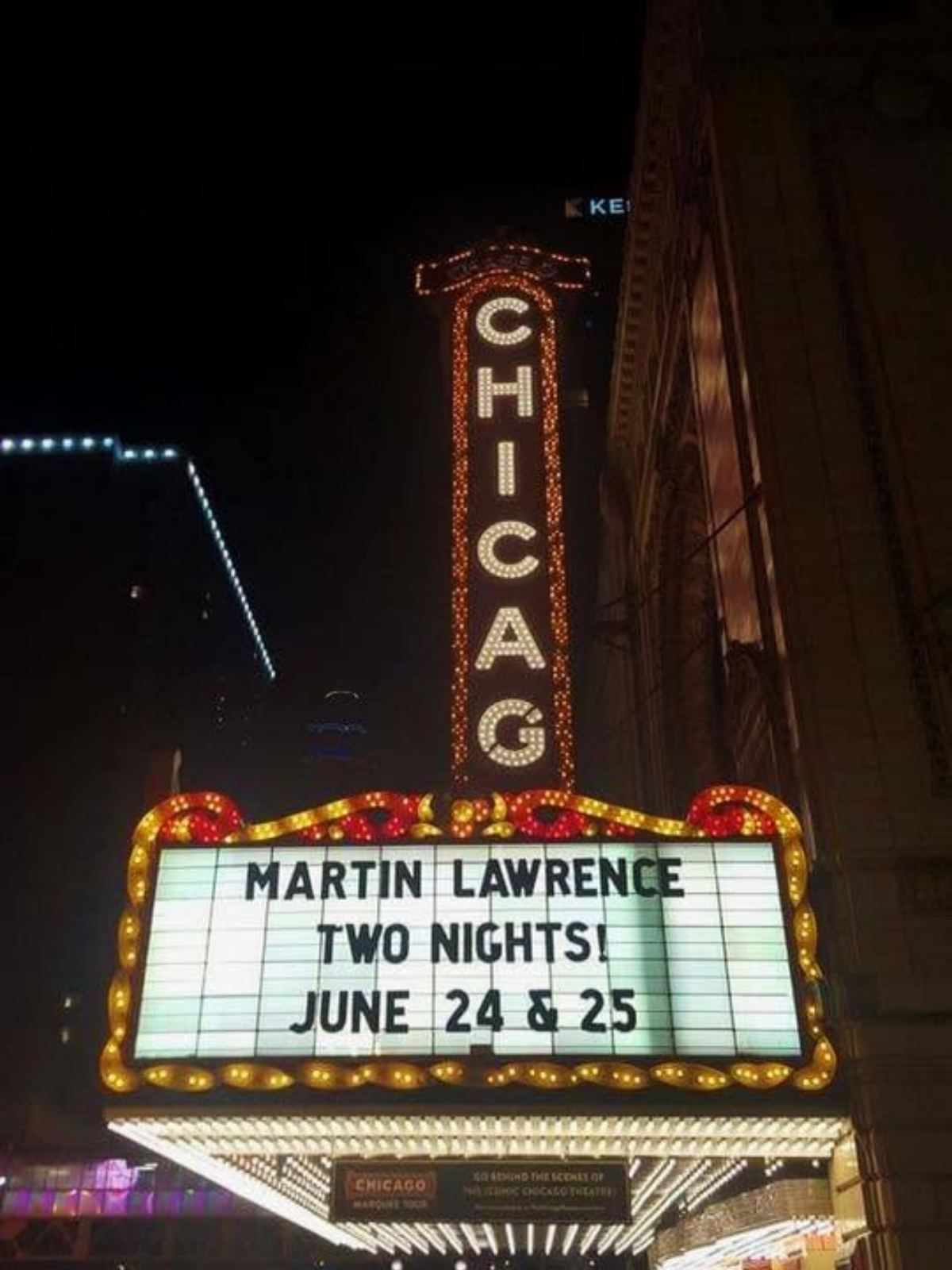 The iconic Chicago Theatre marquee glowing in neon lights at night, announcing a Martin Lawrence show against the dark downtown sky.