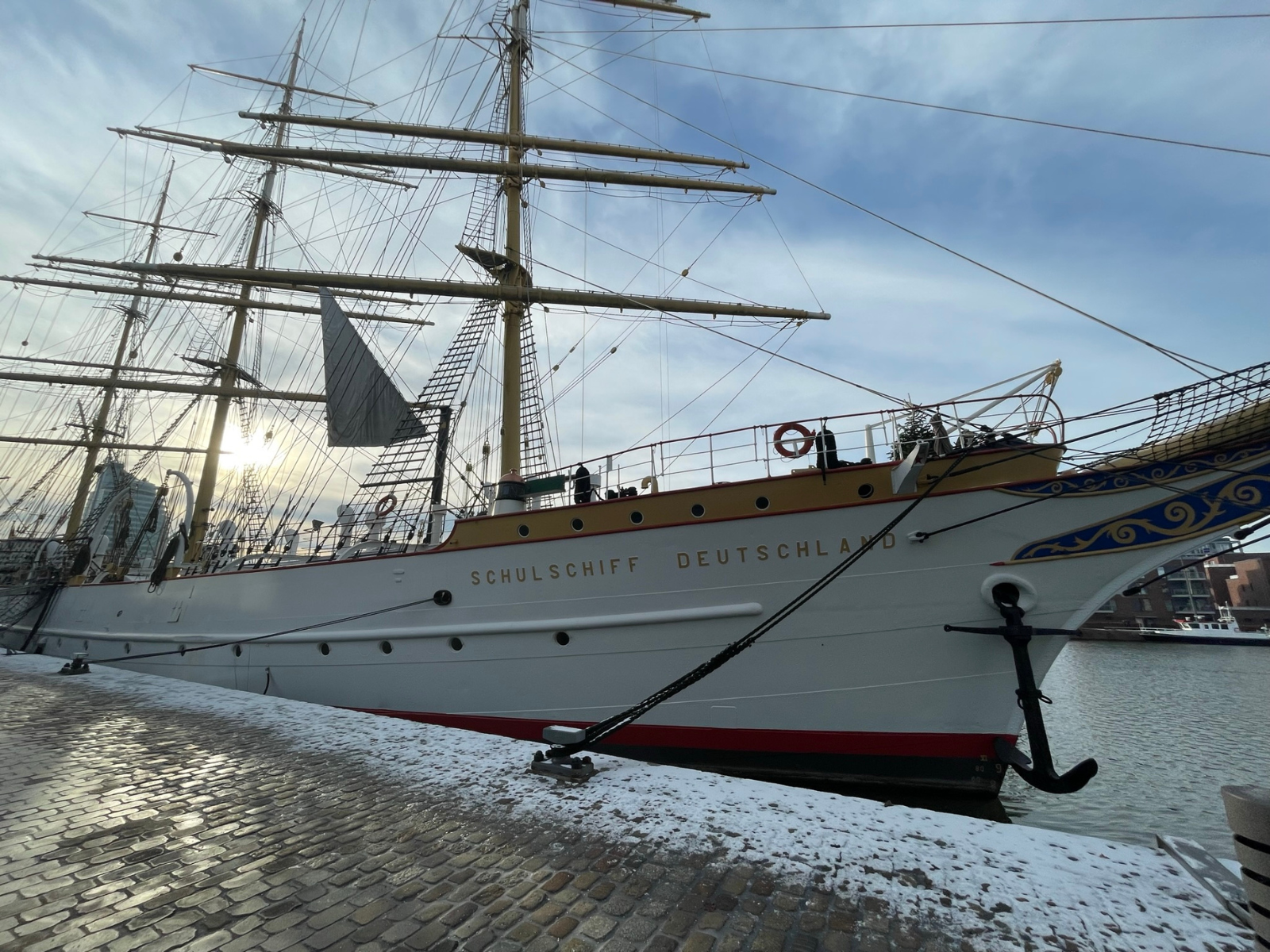 The historic tall ship Schulschiff Deutschland docked in a snow-dusted Bremerhaven harbour.