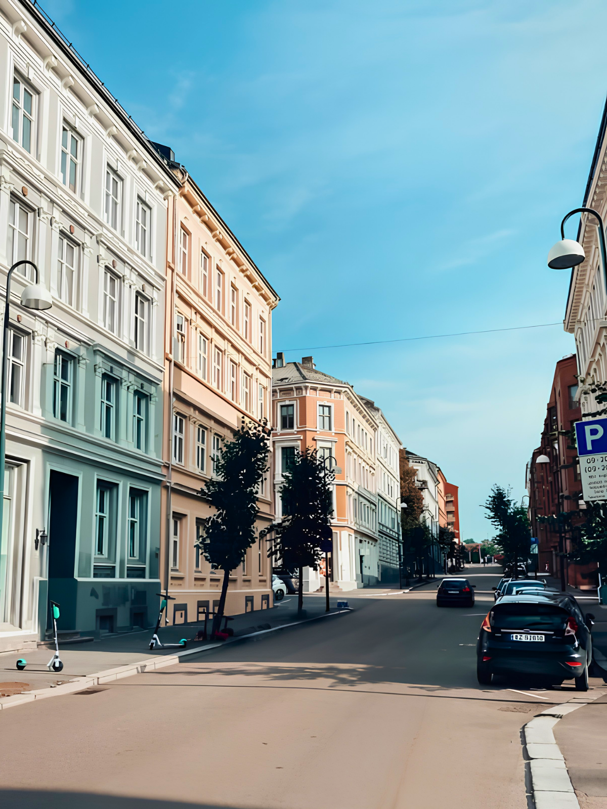 A quiet Oslo street on a bright summer morning, pastel and terracotta building facades lining an almost empty road under a clear blue sky.