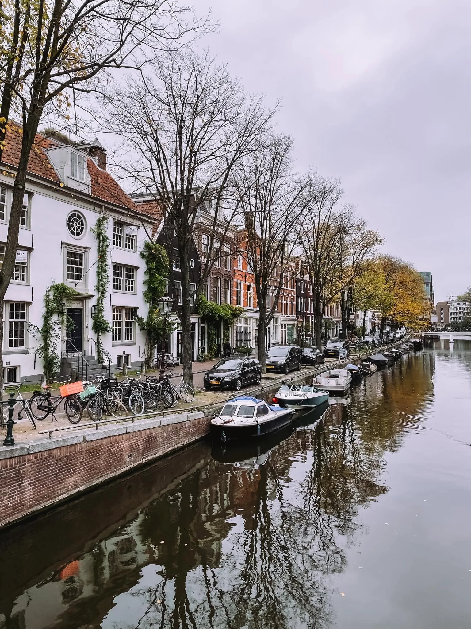 A canal lined with parked bikes, boats, and traditional Amsterdam houses
